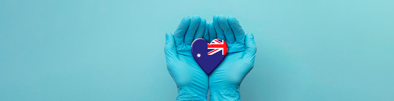 Nurse's hands wearing surgical gloves holding Australia flag heart