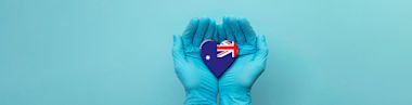 Nurse's hands wearing surgical gloves holding Australia flag heart