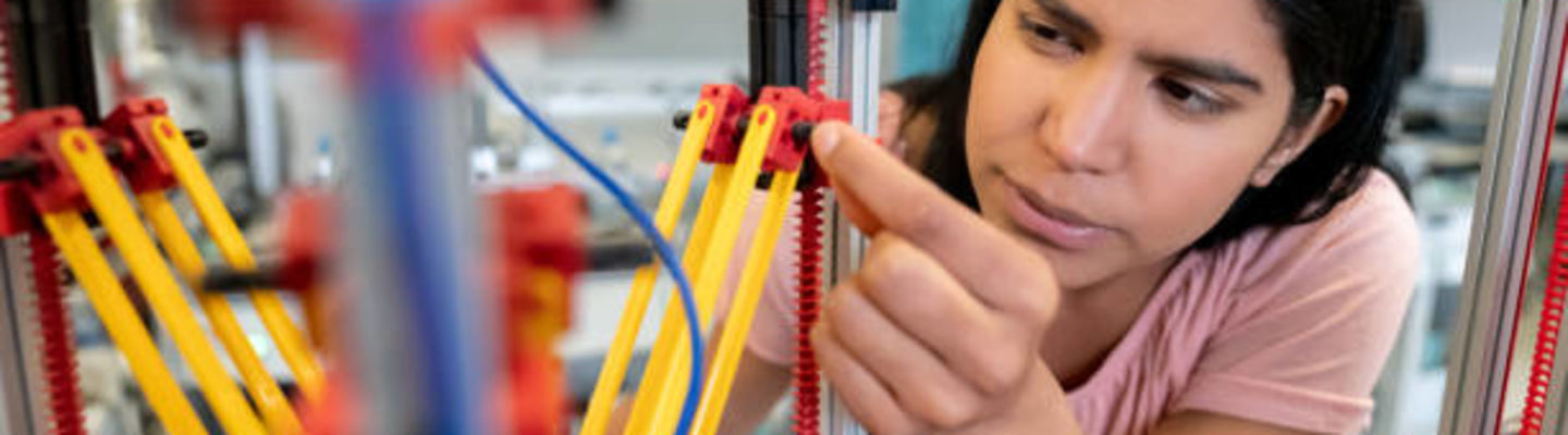 A female student building a robot in a lab.