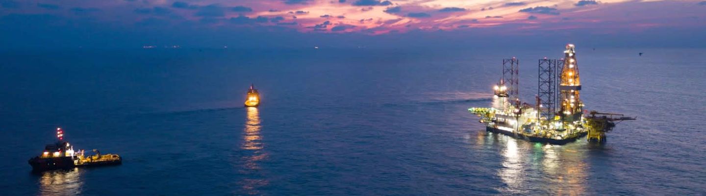 An offshore jack up rig in the middle of the sea during sunset.