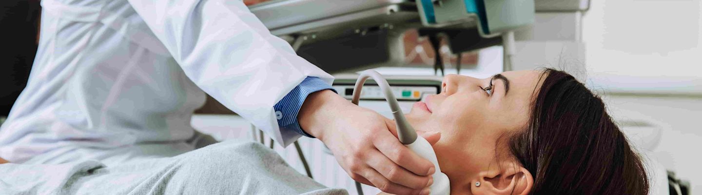 A woman lies on the examining table while the doctor checks her