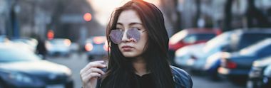 An international student wearing sunglasses in a city street.