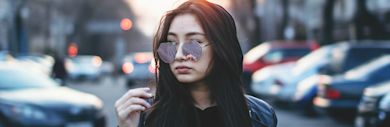 An international student wearing sunglasses in a city street.