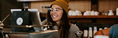 woman smiling at coffee machine in cafe