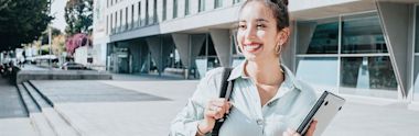 woman holding laptop smiling outside building