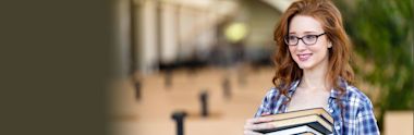 A female international student holding books in a university campus