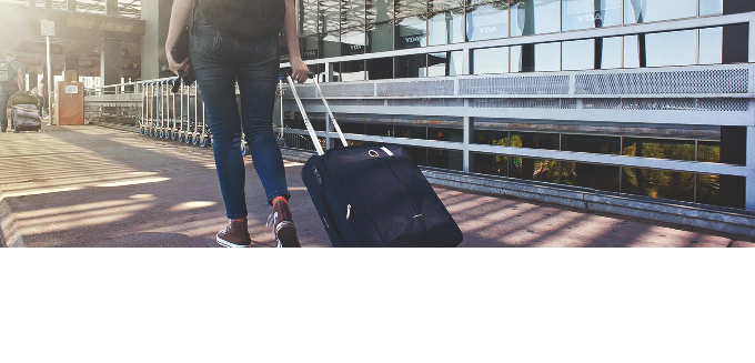 A female student carrying a suitcase in the airport
