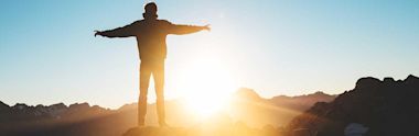 A silhouette of a student viewing the sunrise from a cliff
