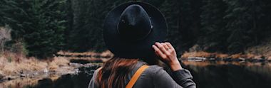An international student wearing a hat watches the scenic beauty of a lake in Canada