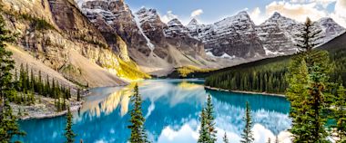Turquoise waters of Moraine Lake reflect snow-capped Rocky Mountain peaks and evergreen forests in Banff National Park, Canada