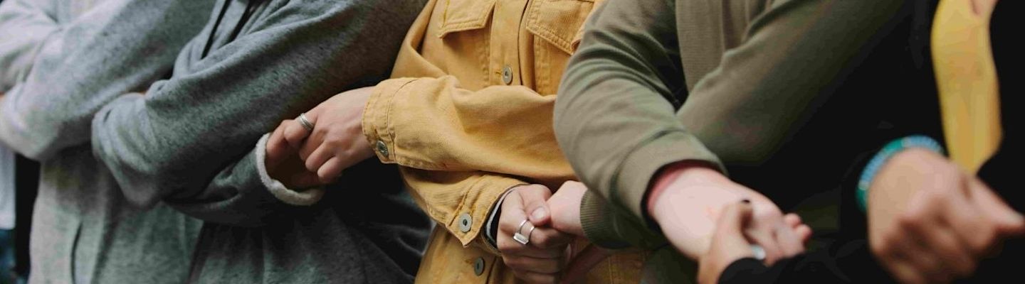A group of people holding hands with each other making a chain.