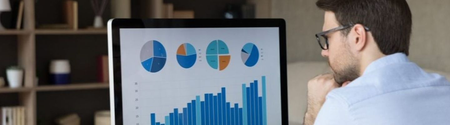 An Economics student looking at a computer monitor, analyzing project stats.