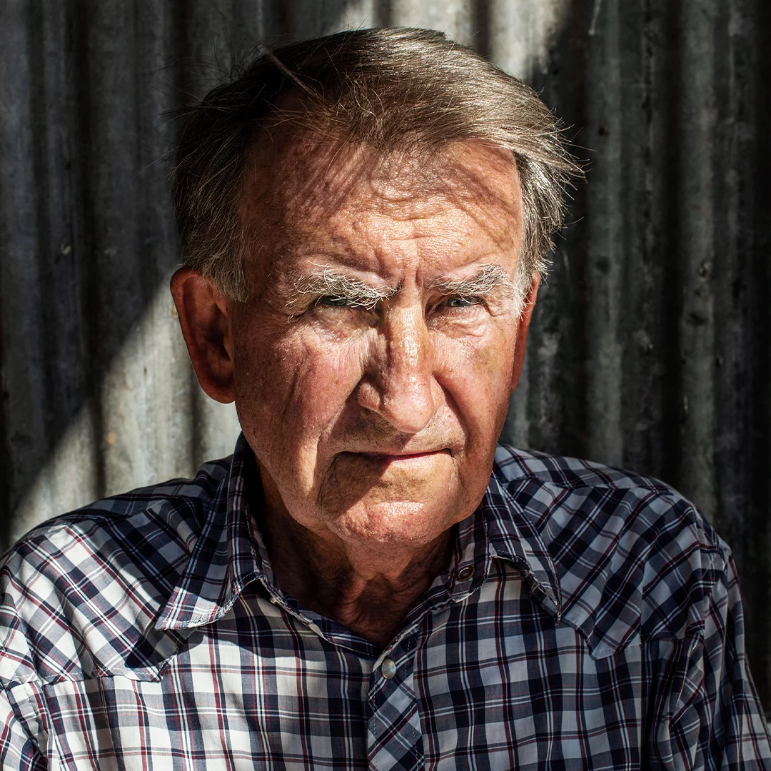 Forfatterportrett av Gerald Murnane, sittende foran en metallisk bakgrunn.