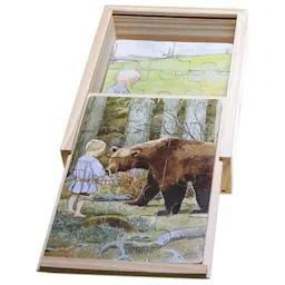 Träpussel med illustrationer av ett barn och en björn i skogen, förpackat i en träask.
