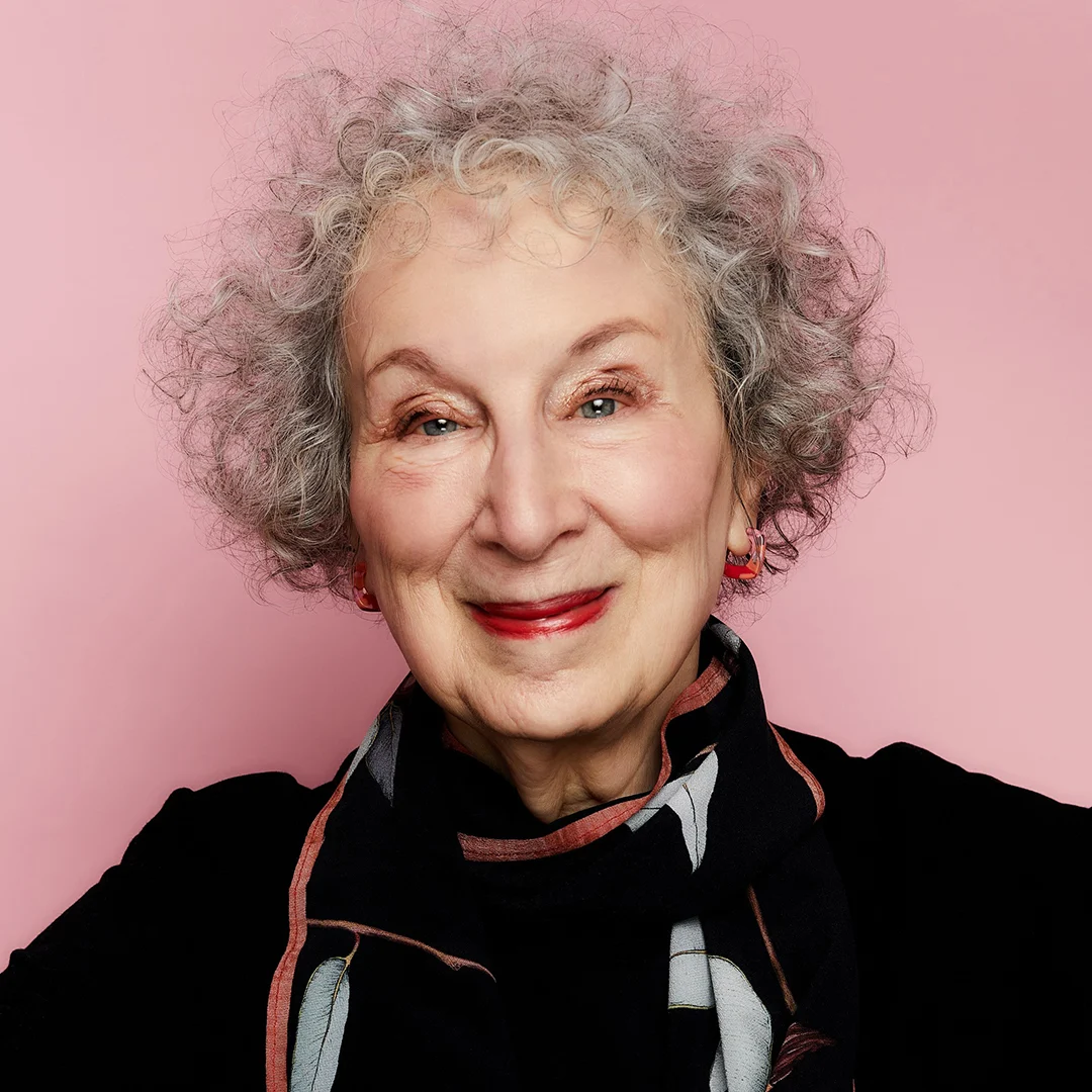 Författarporträtt av Margaret Atwood med lockigt grått hår och svart sjal mot rosa bakgrund.