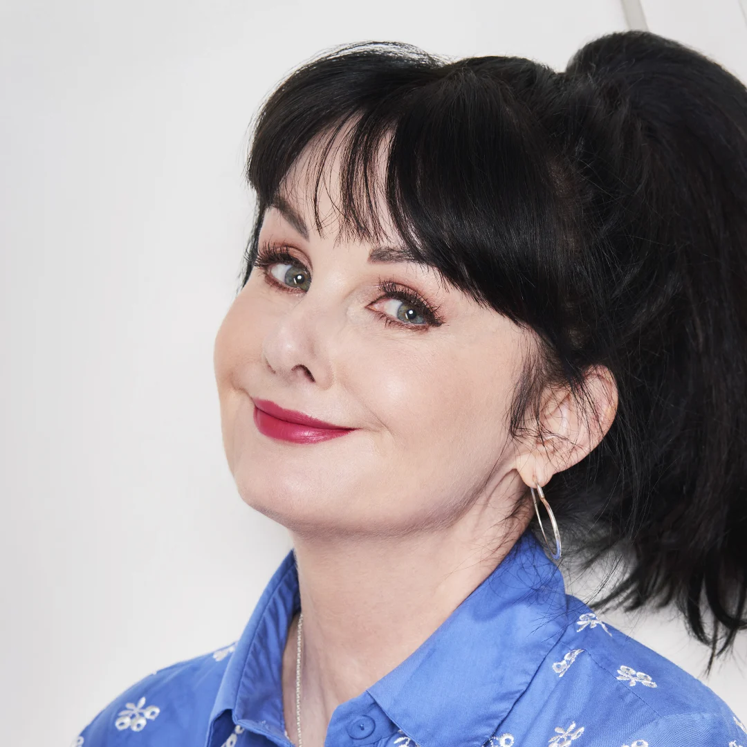 Författarporträtt av Marian Keyes, klädd i en blå skjorta med mönster.