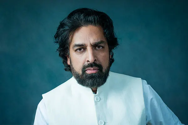 Forfatterportrett av Zahid Ali, iført en hvit jakke med en mørk bakgrunn.