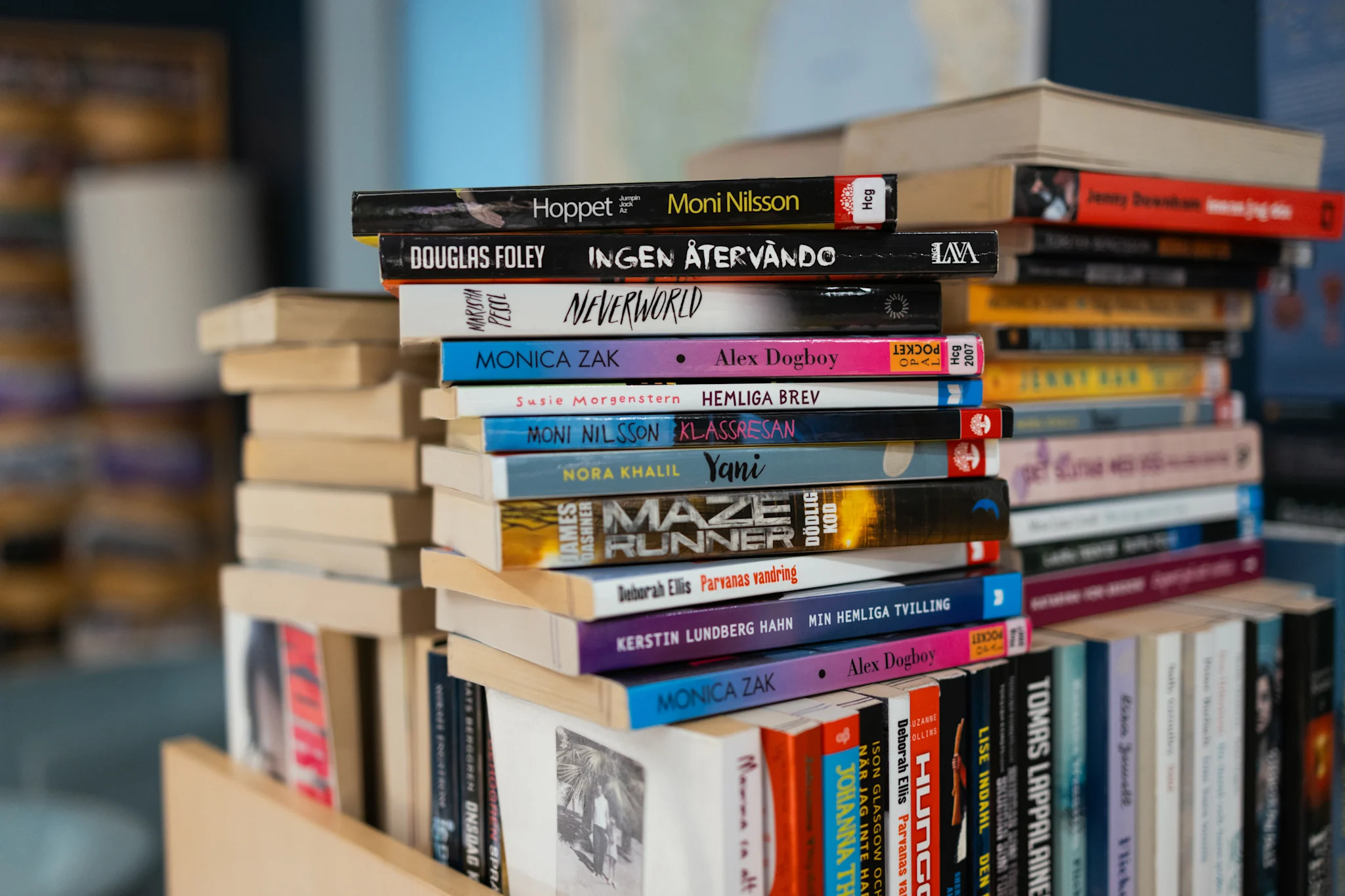 En stapel av böcker i ett bibliotek med olika titlar och färger.