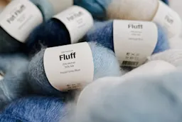 Flere garnnøster av silke mohair i blå og grå nyanser med etiketter som viser innholdet.