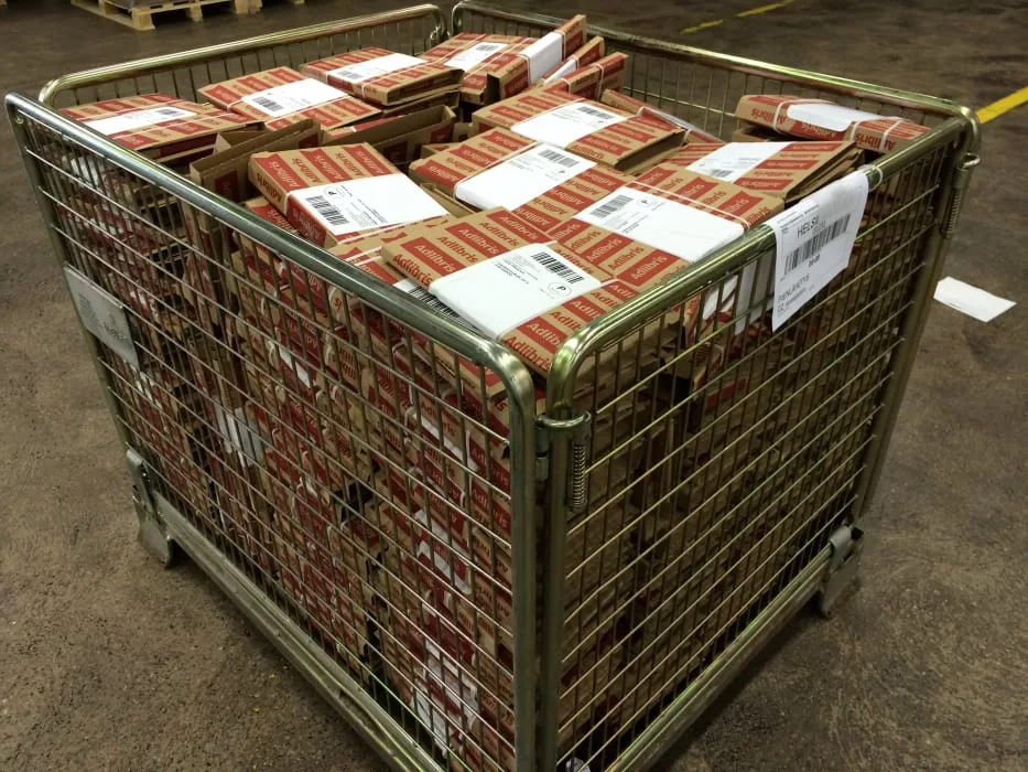 Metallikori täynnä Adlibris-merkittyjä paketteja, näkyy varastotilassa.