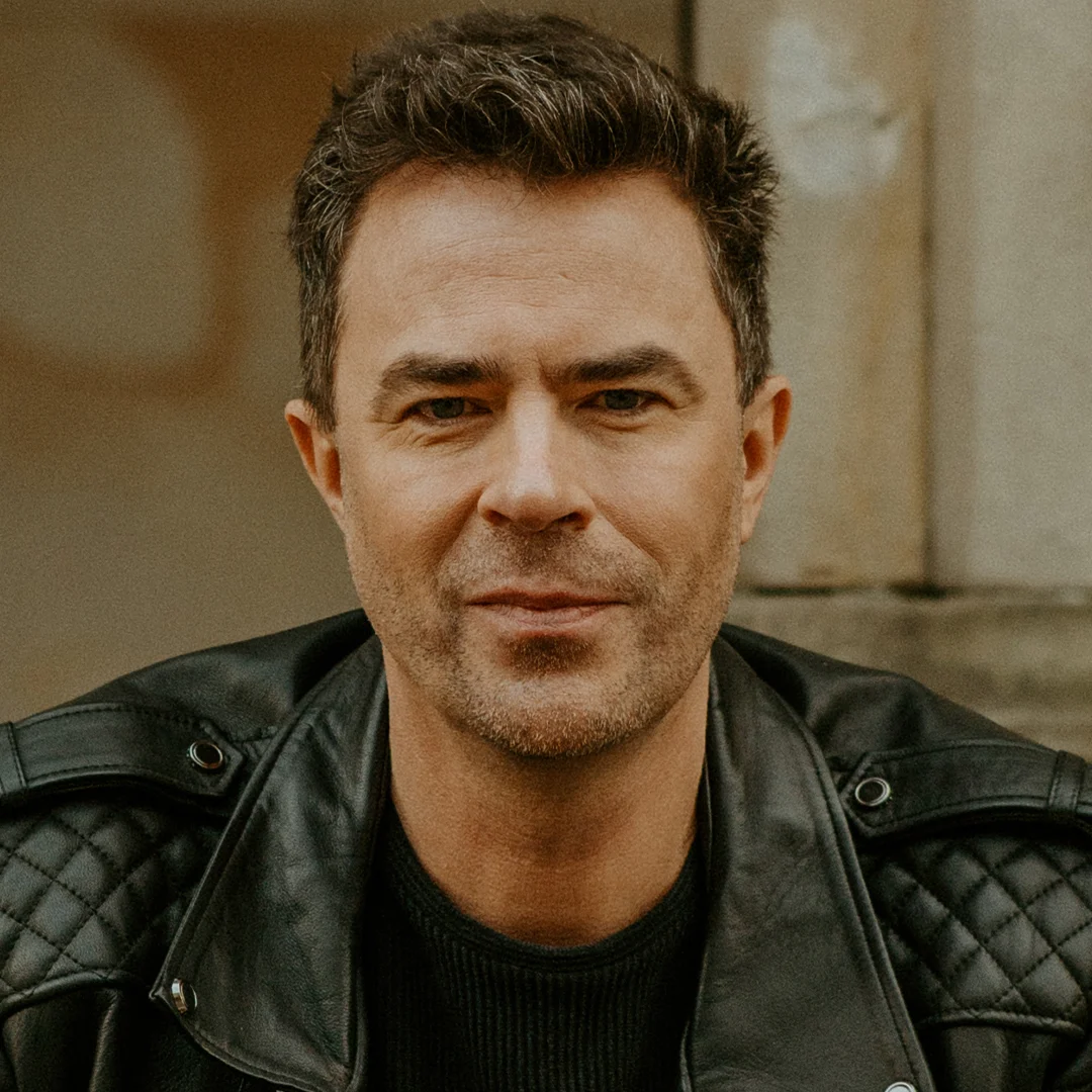 Författarporträtt av Elias Våhlund, sittande med händerna ihop i en läderjacka.