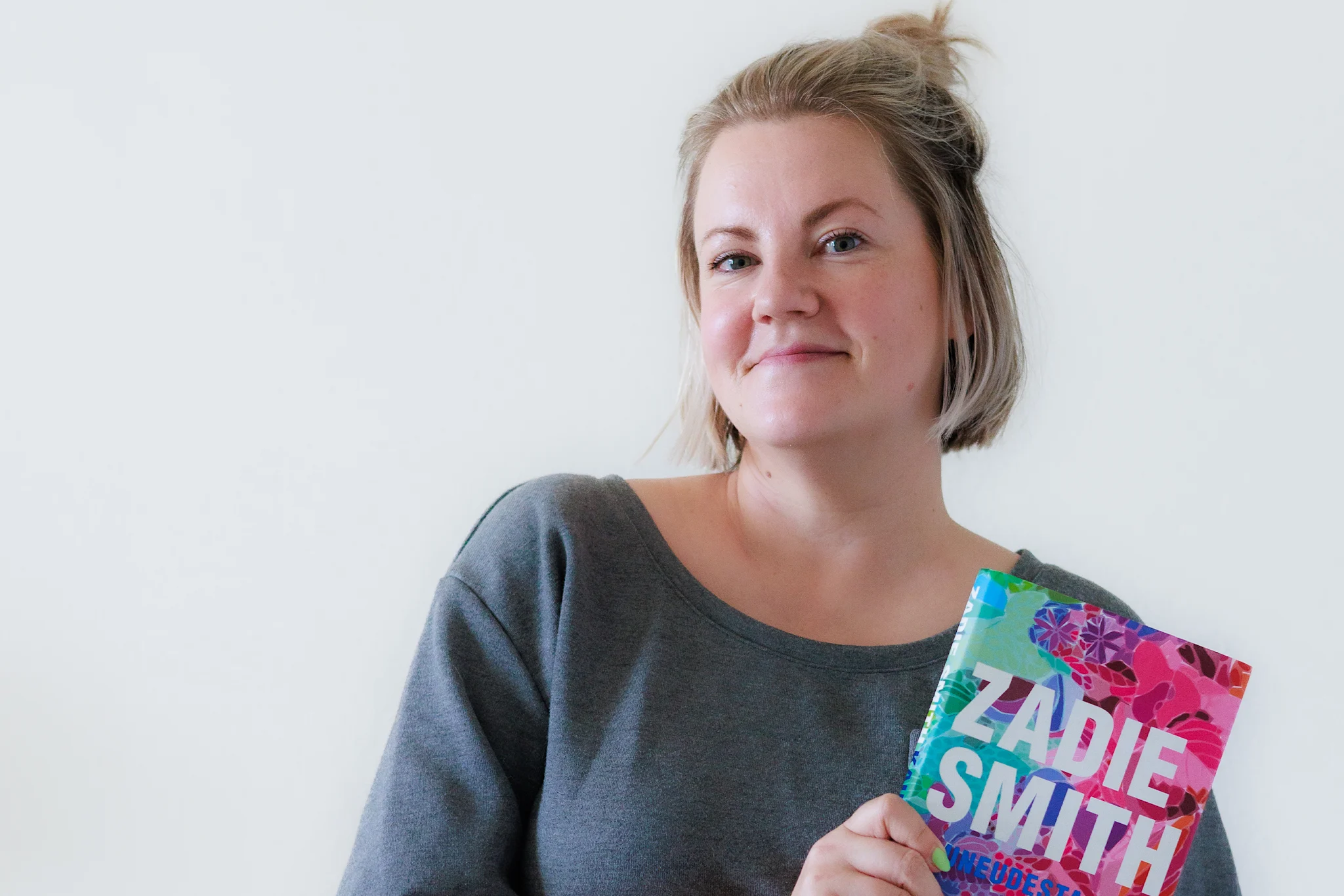 Henkilö pitää Zadie Smithin kirjaa valkoista taustaa vasten.