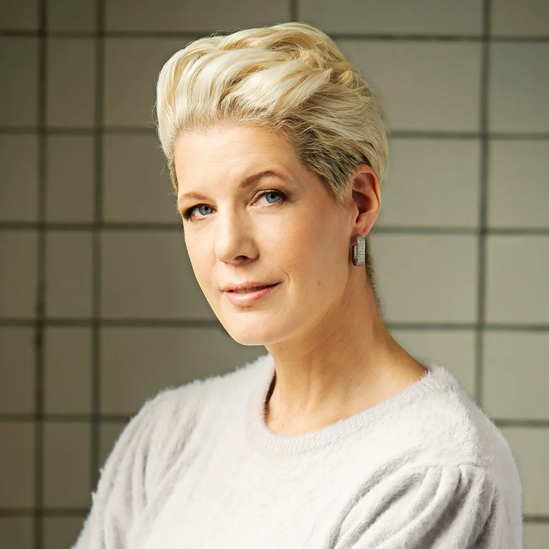 Porträtt av författaren Anna Karolina med kort blont hår och örhängen.