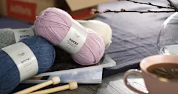 Bilde av ulike garnnøster med etiketter, en kaffekopp og en vase på et bord.