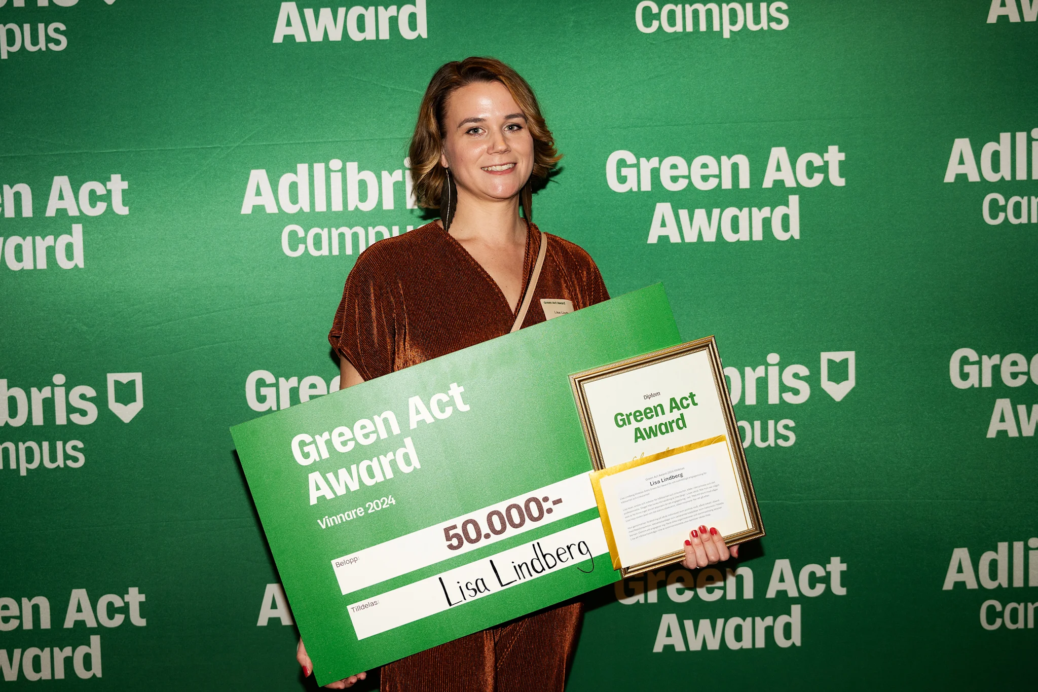 Person står med en stor check och ett diplom för Green Act Award 2024.