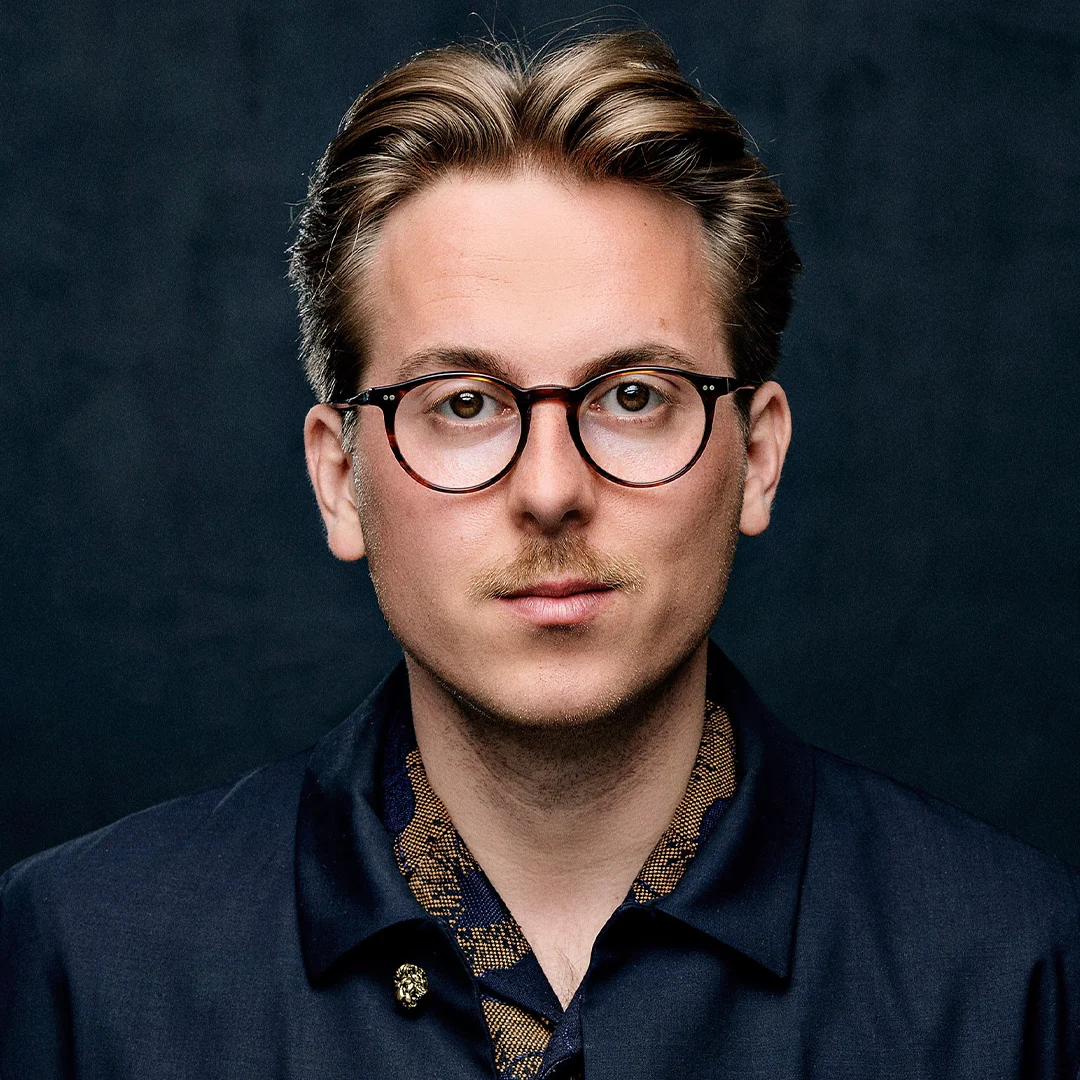 Portrett av forfatteren Thomas Korsgaard, iført en mørk jakke med mønstret krage.
