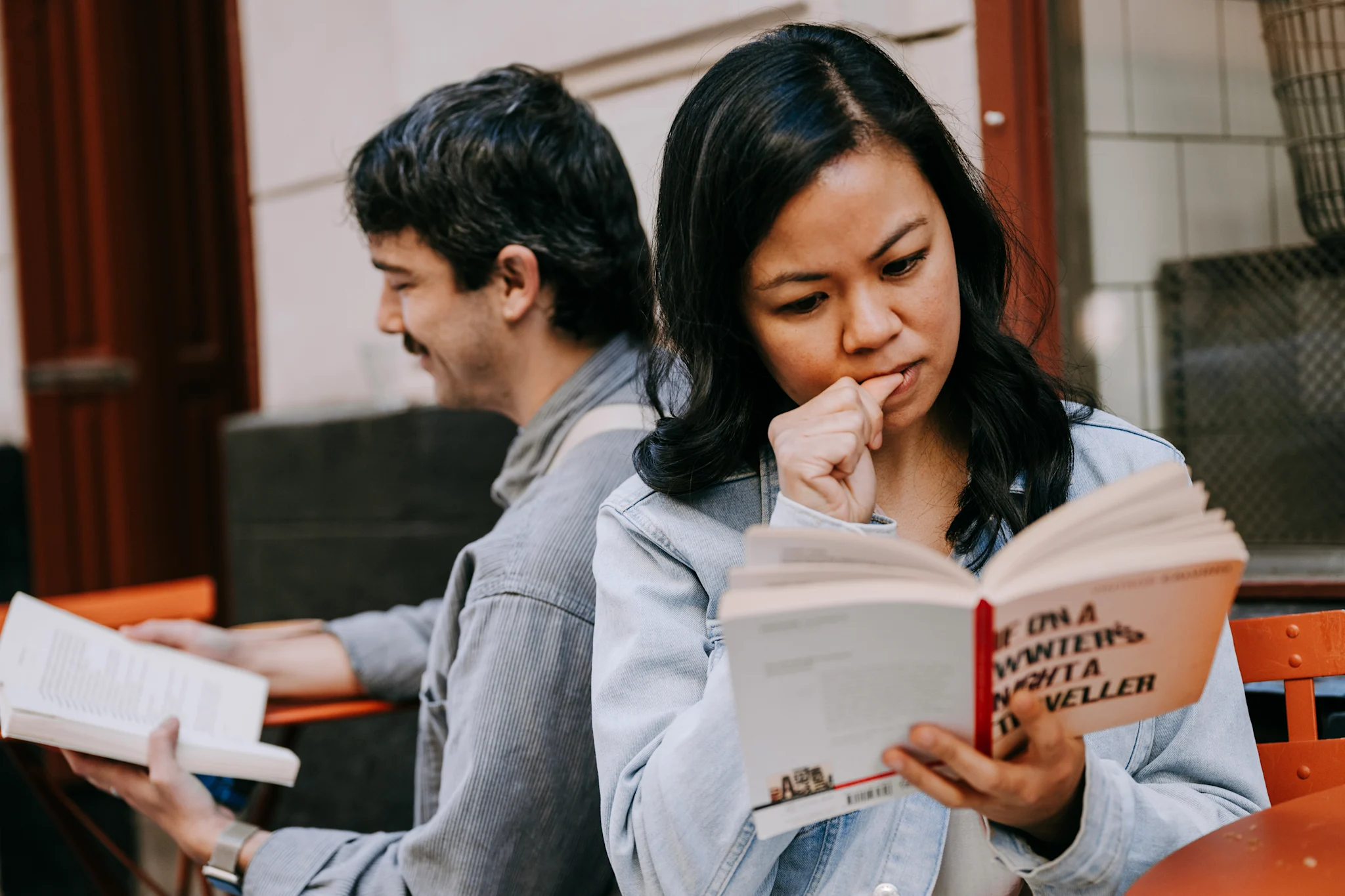 To personer sitter ute med bøker, den ene blar i en bok mens den andre holder en bok i hånden.
