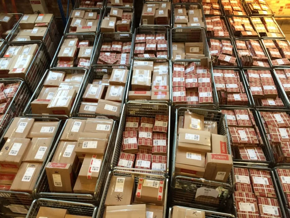 Näkymä paketeista pinottuna metallikoreihin logistiikkakeskuksessa.