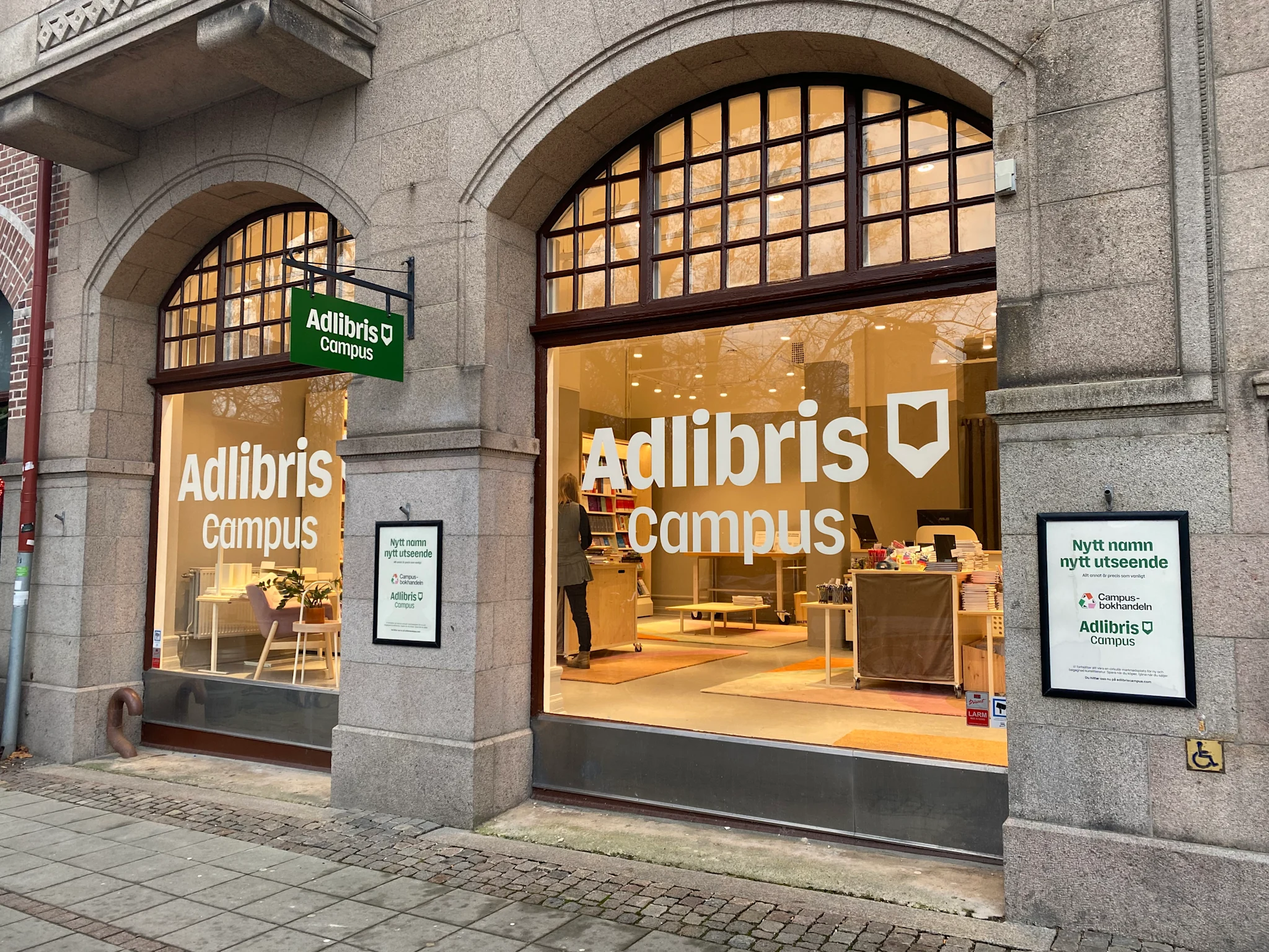 Bild av Adlibris Campus Lunds butik med stora fönster och skyltar som visar namnet.