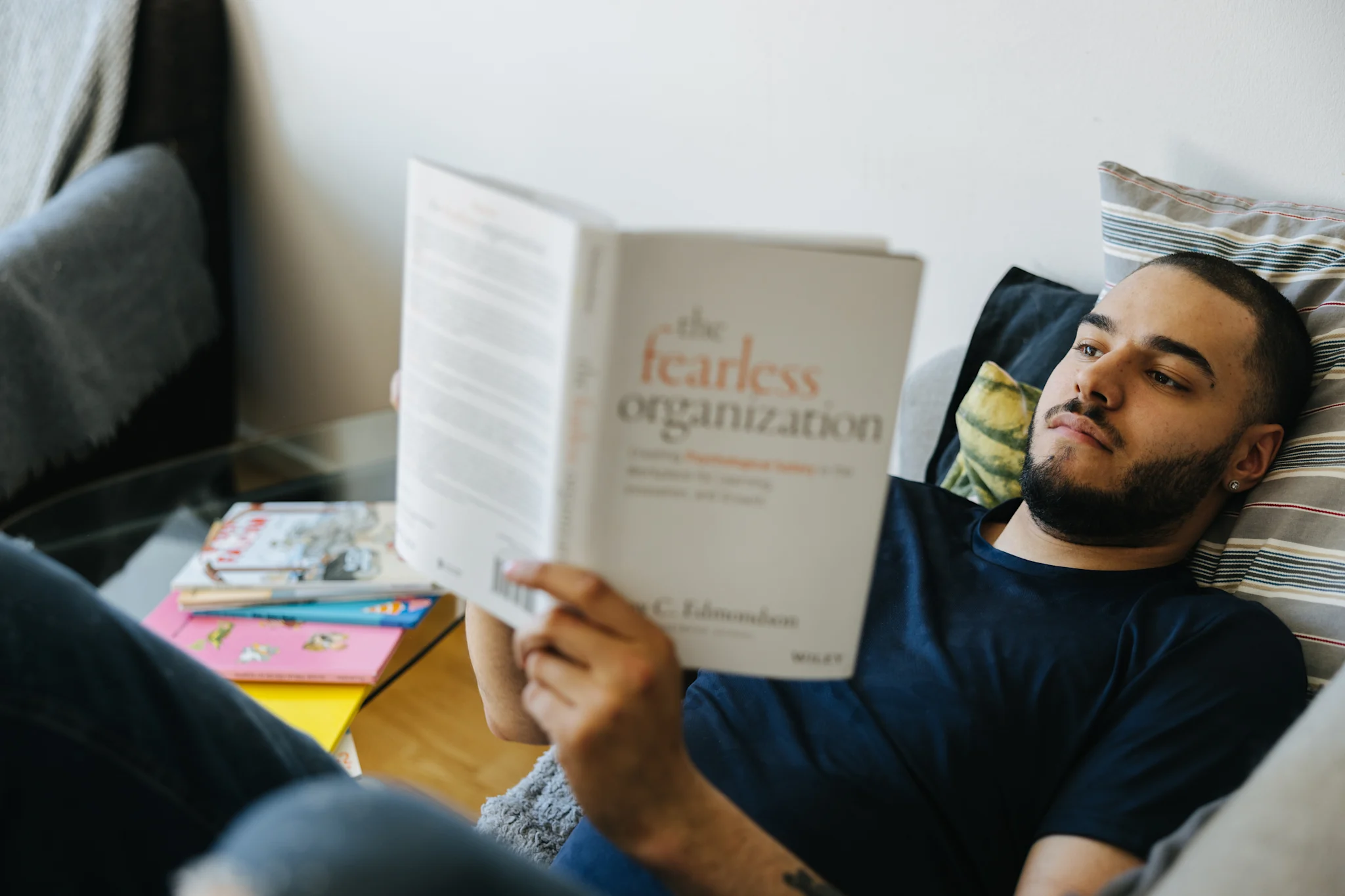 Henkilö makaa sohvalla ja lukee kirjaa 'The Fearless Organization'.