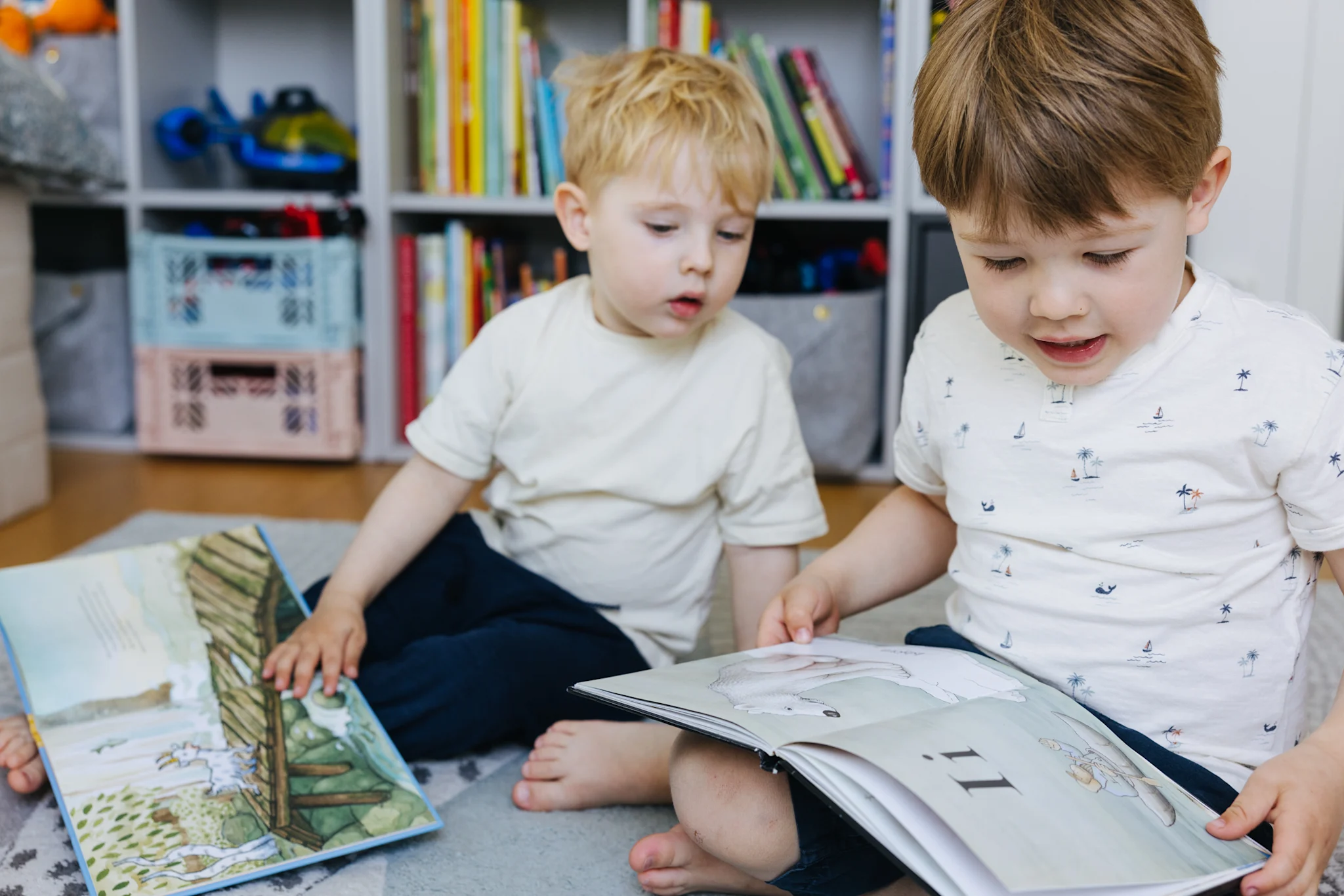 To barn sitter på gulvet og leser bøker i et rom med hyller fulle av bøker.