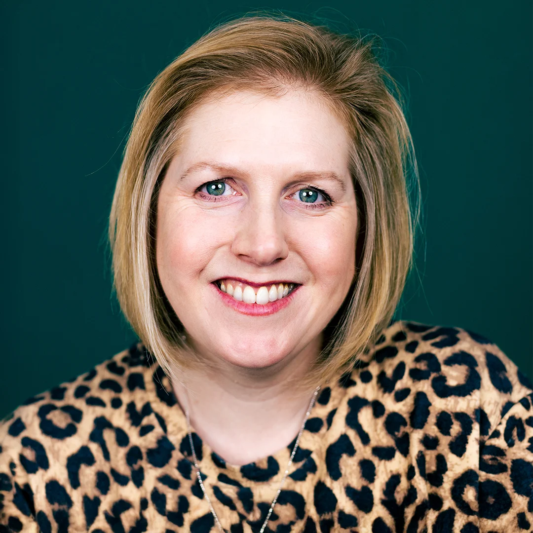 Kirjailijaportretti Clare Mackintoshista, päällä leopardikuvioinen paita vihreää taustaa vasten.