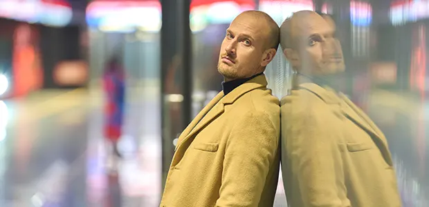 Max Seckin muotokuva modernissa ympäristössä, heijastuma lasiseinässä.