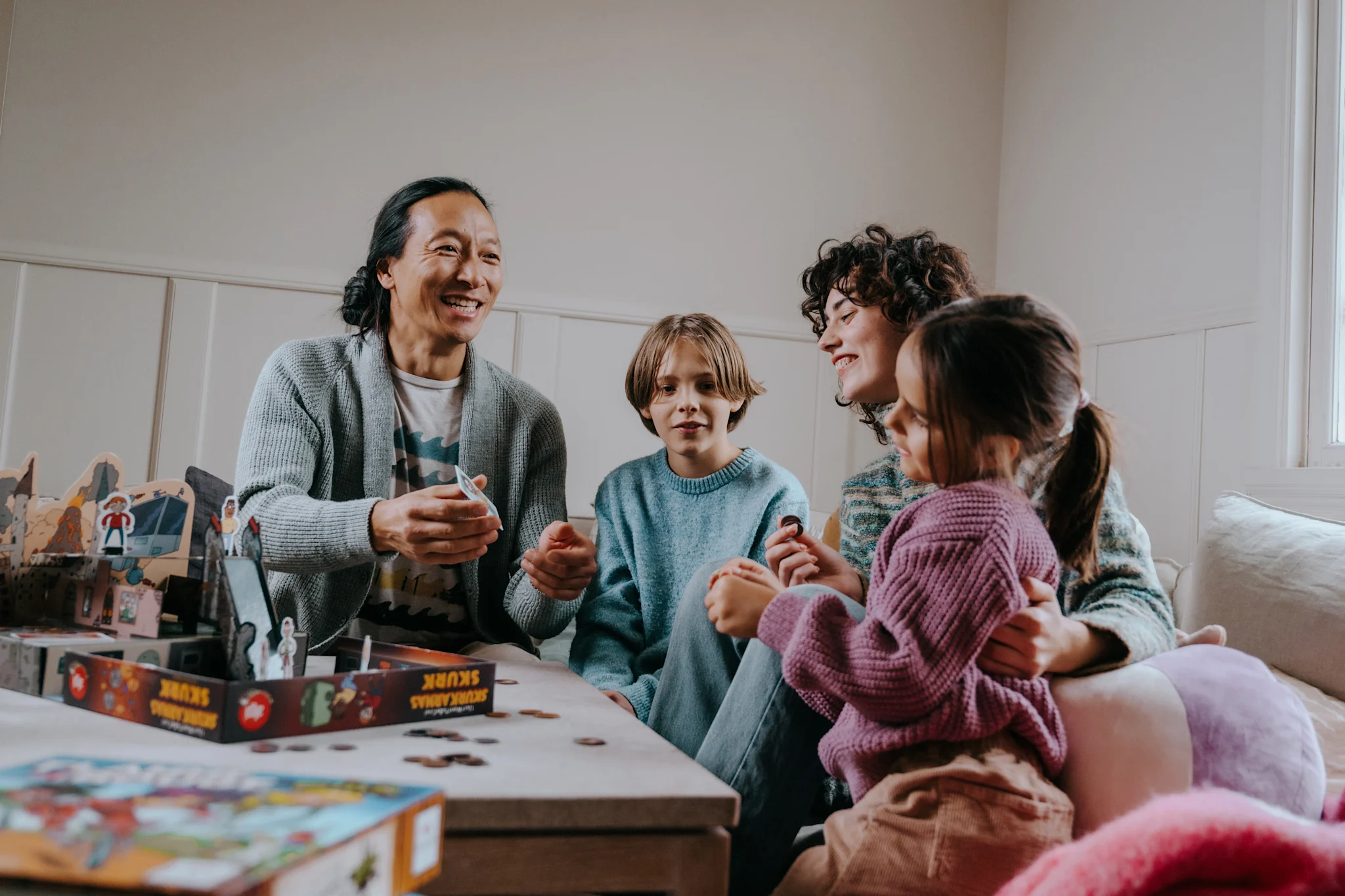 Perhe pelaa lautapeliä yhdessä mukavassa olohuoneessa.