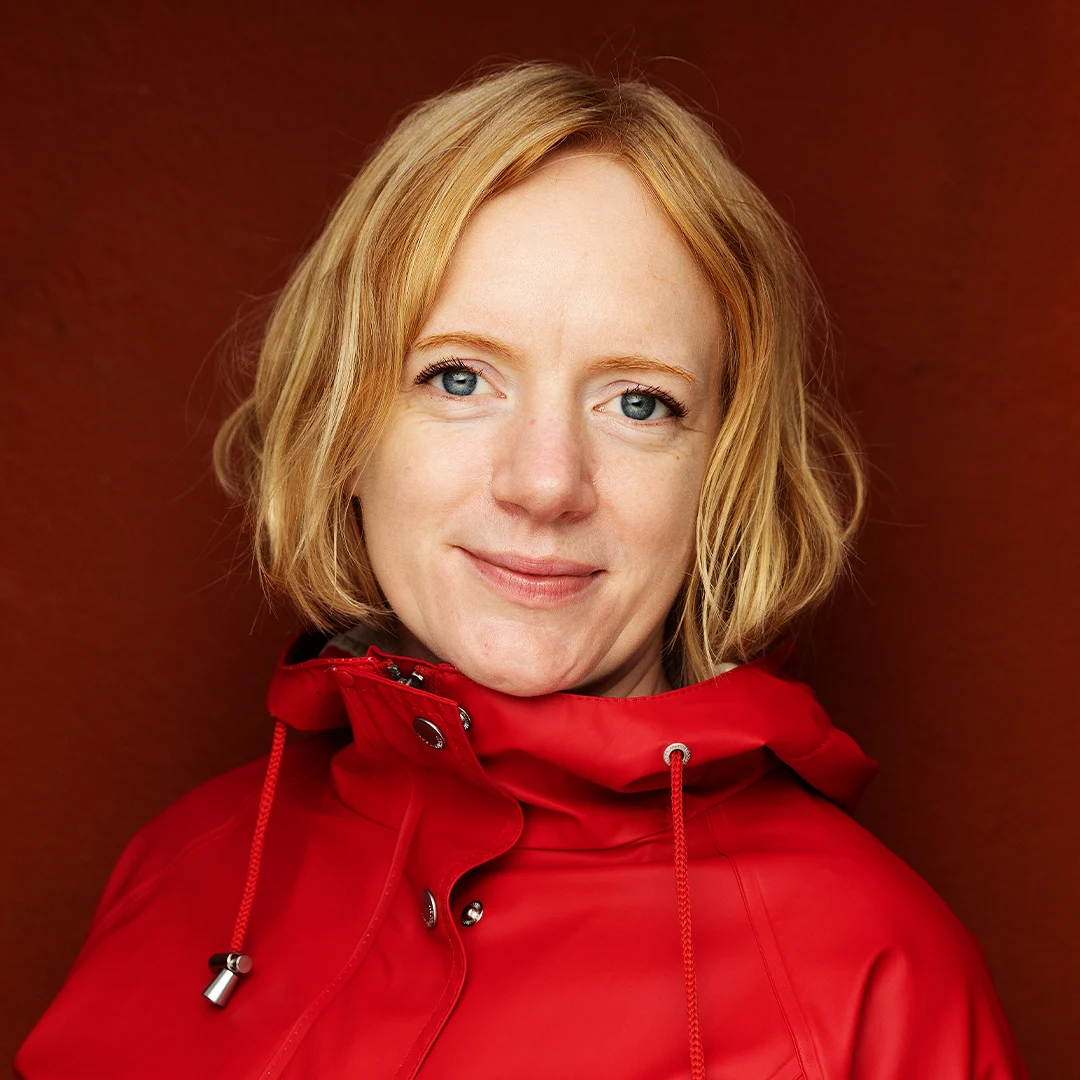 Forfatterportrett av Erika Fatland i en rød jakke mot en mørk bakgrunn.