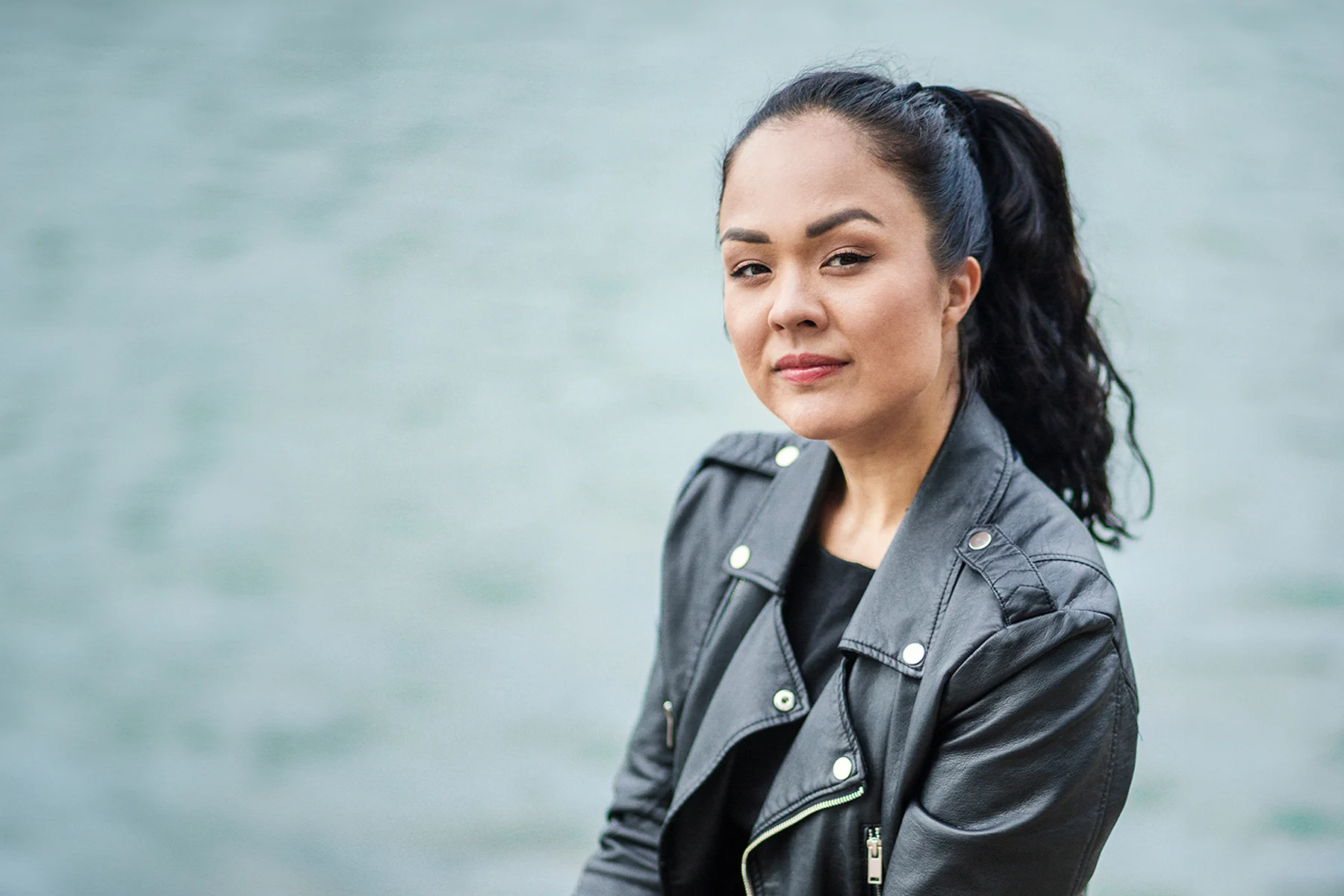 Kirjailijan muotokuva Sita Salmisesta, pukeutuneena mustaan takkiin, sumea tausta.