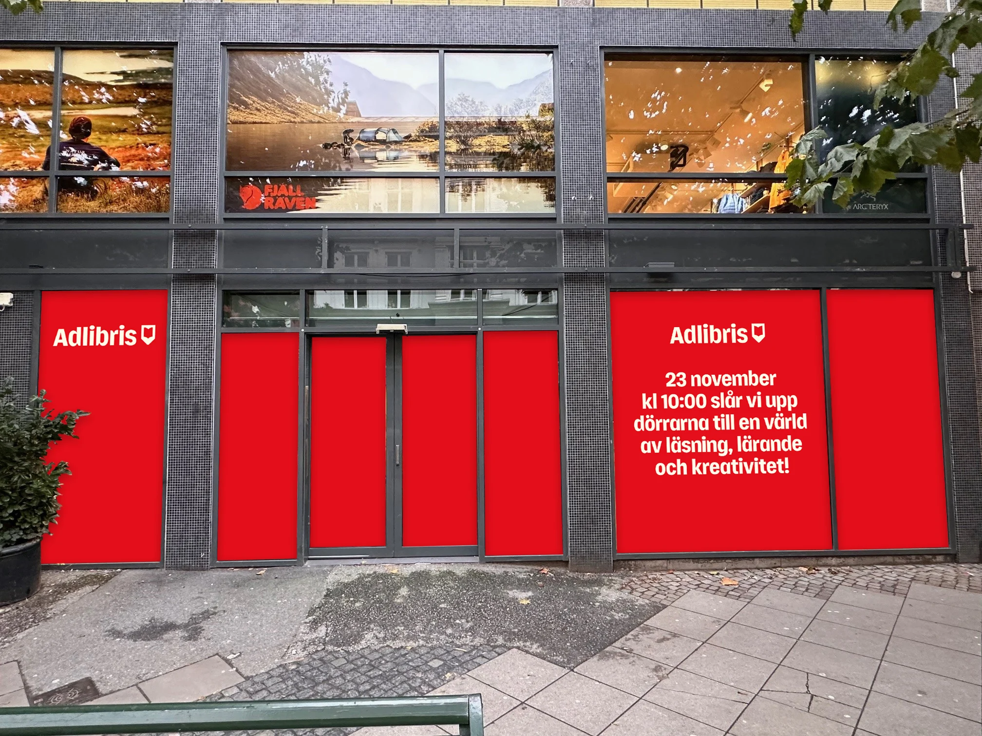 Fasaden till Adlibris i Malmö med röda dörrar och information om öppningen den 23 november.