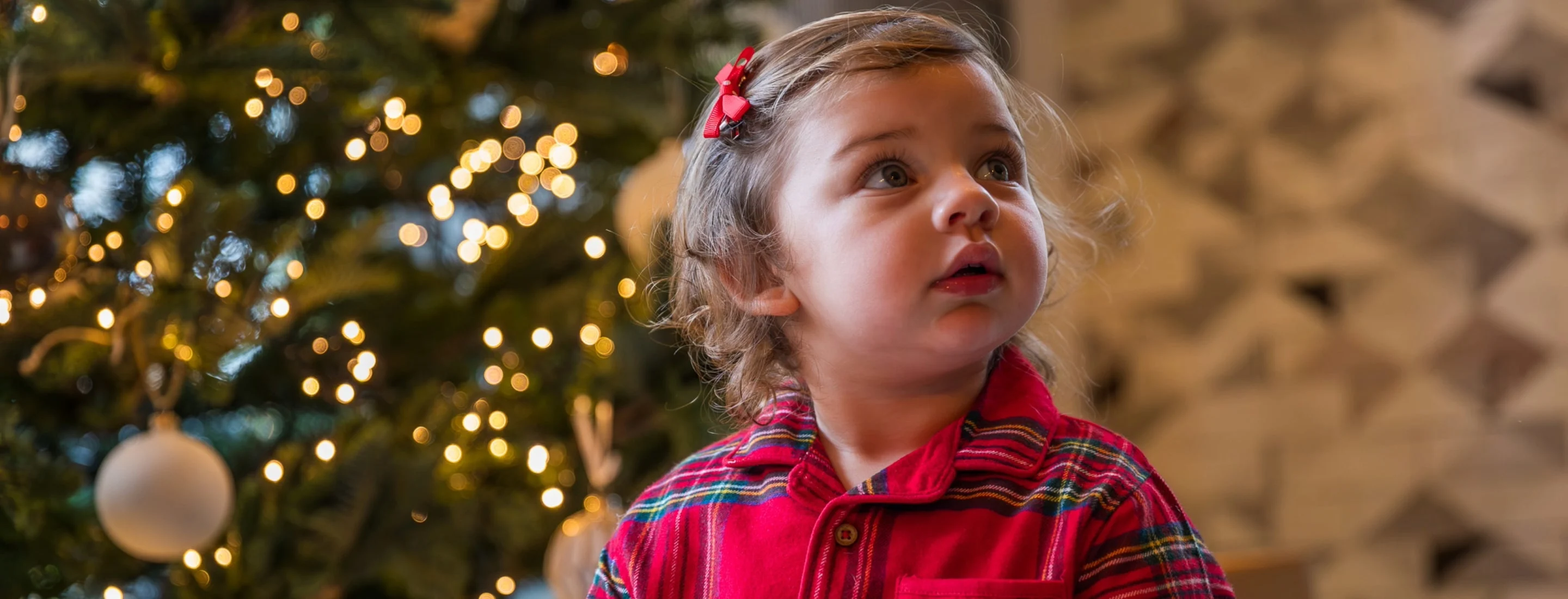 Young girl stood in front of christmas tree