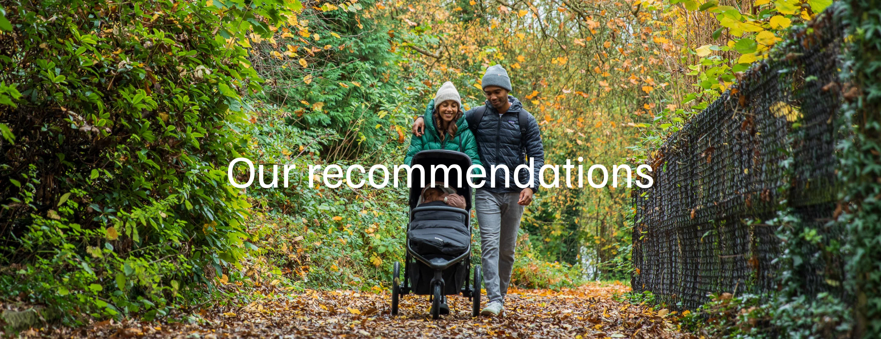 a family walking through a park during autumn pushing a running pushchair