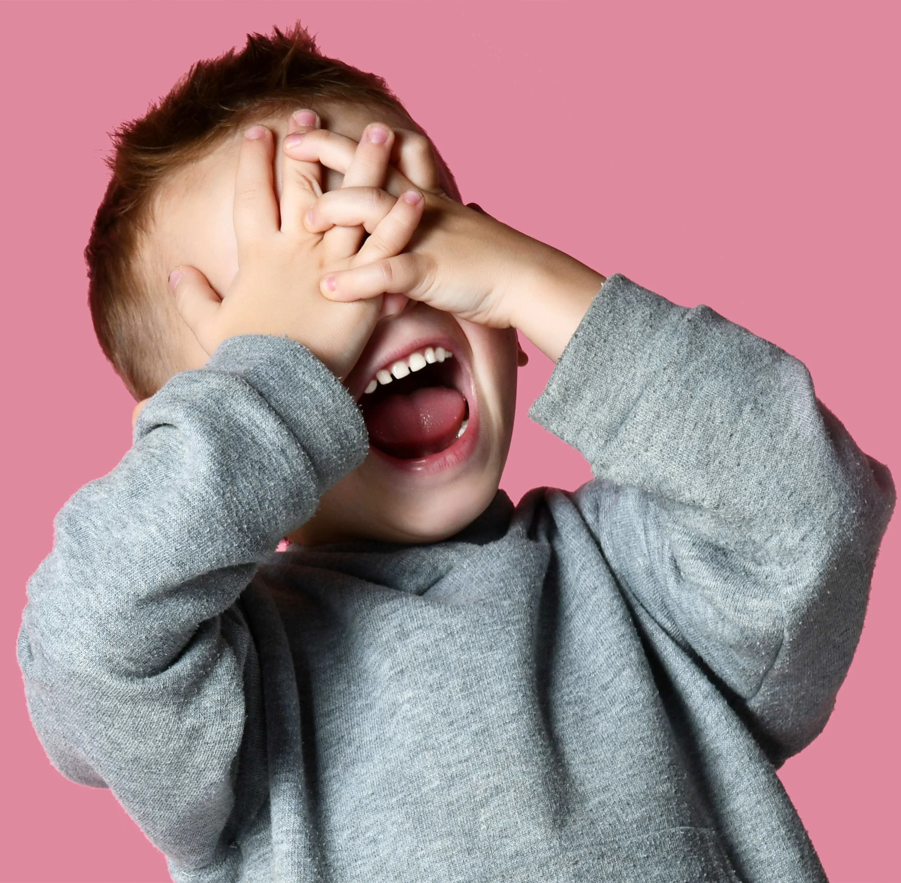 A toddler covering their eyes