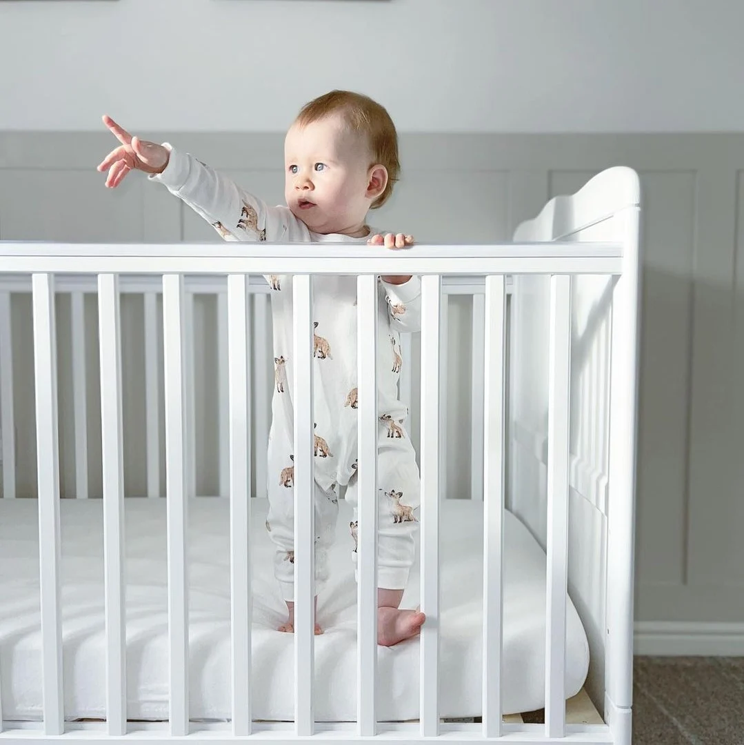 Baby in cot pointing