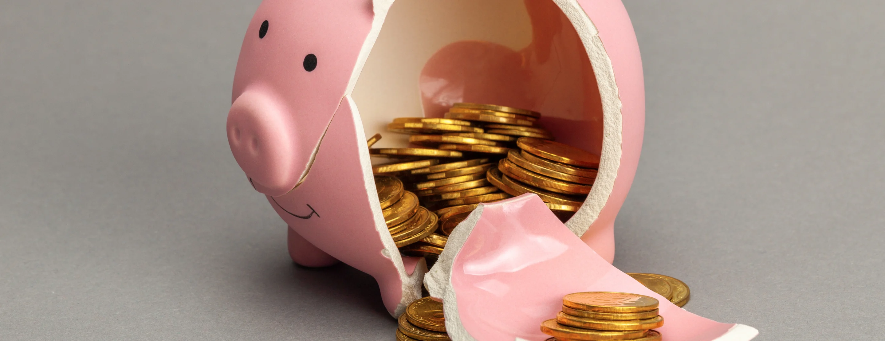A broken pink piggy bank with money spilling out