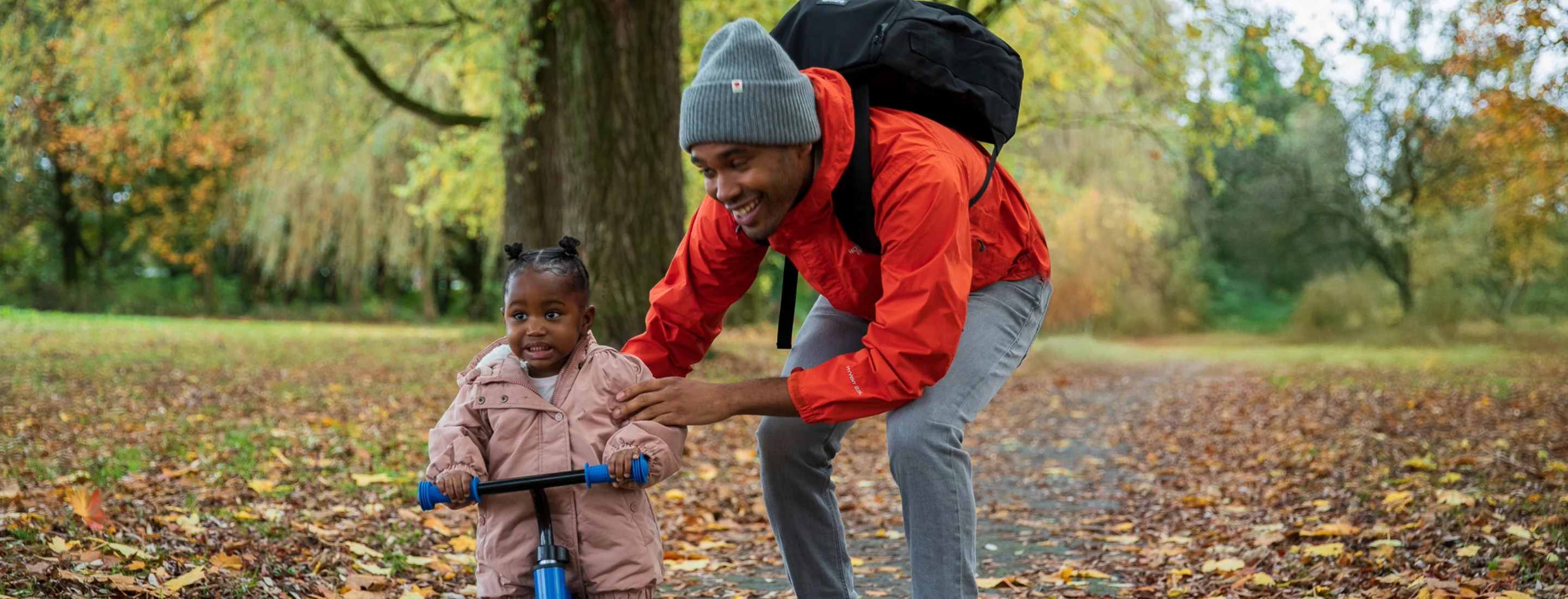 dad and daughter with a scooter in the park on an autumn day