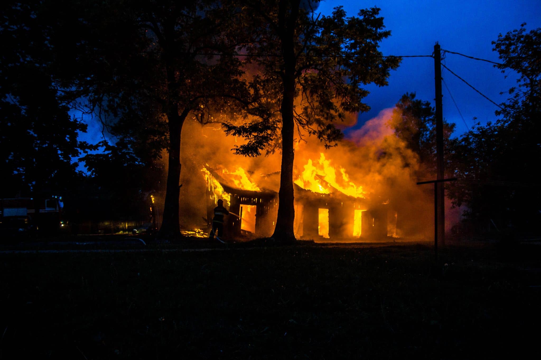 Natural disaster, fire of a wooden house in the forest. Firefighters extinguish the flame.