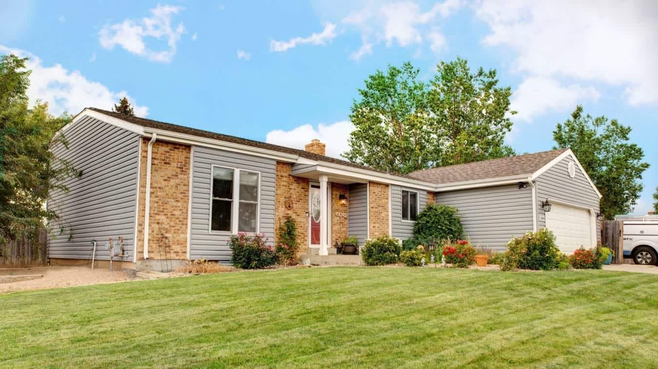 house with gray vinyl siding installed by Colorado Siding Repair and brick