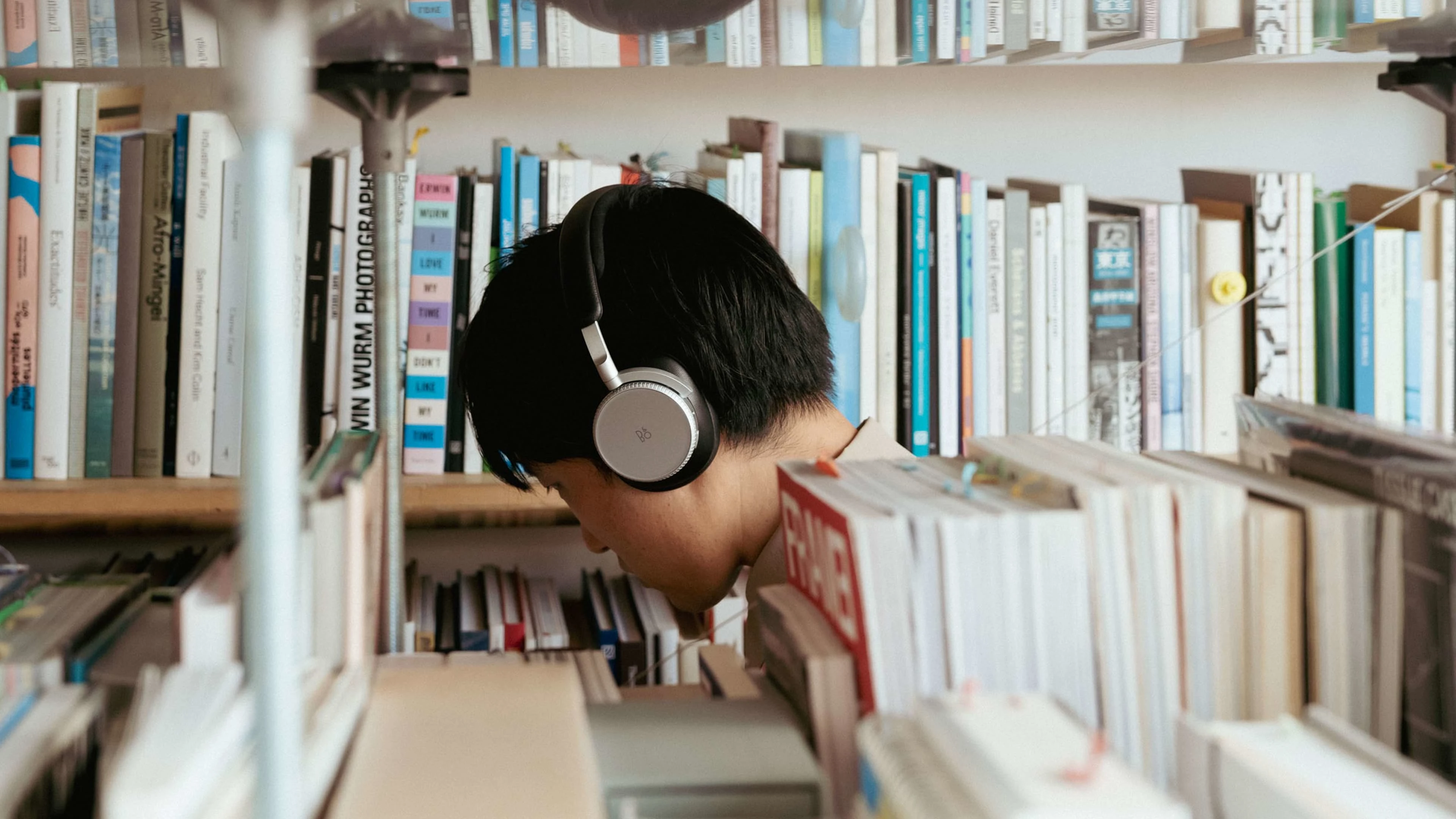 Shuta Hasunum listening to music on the Beoplay H100 in a library 